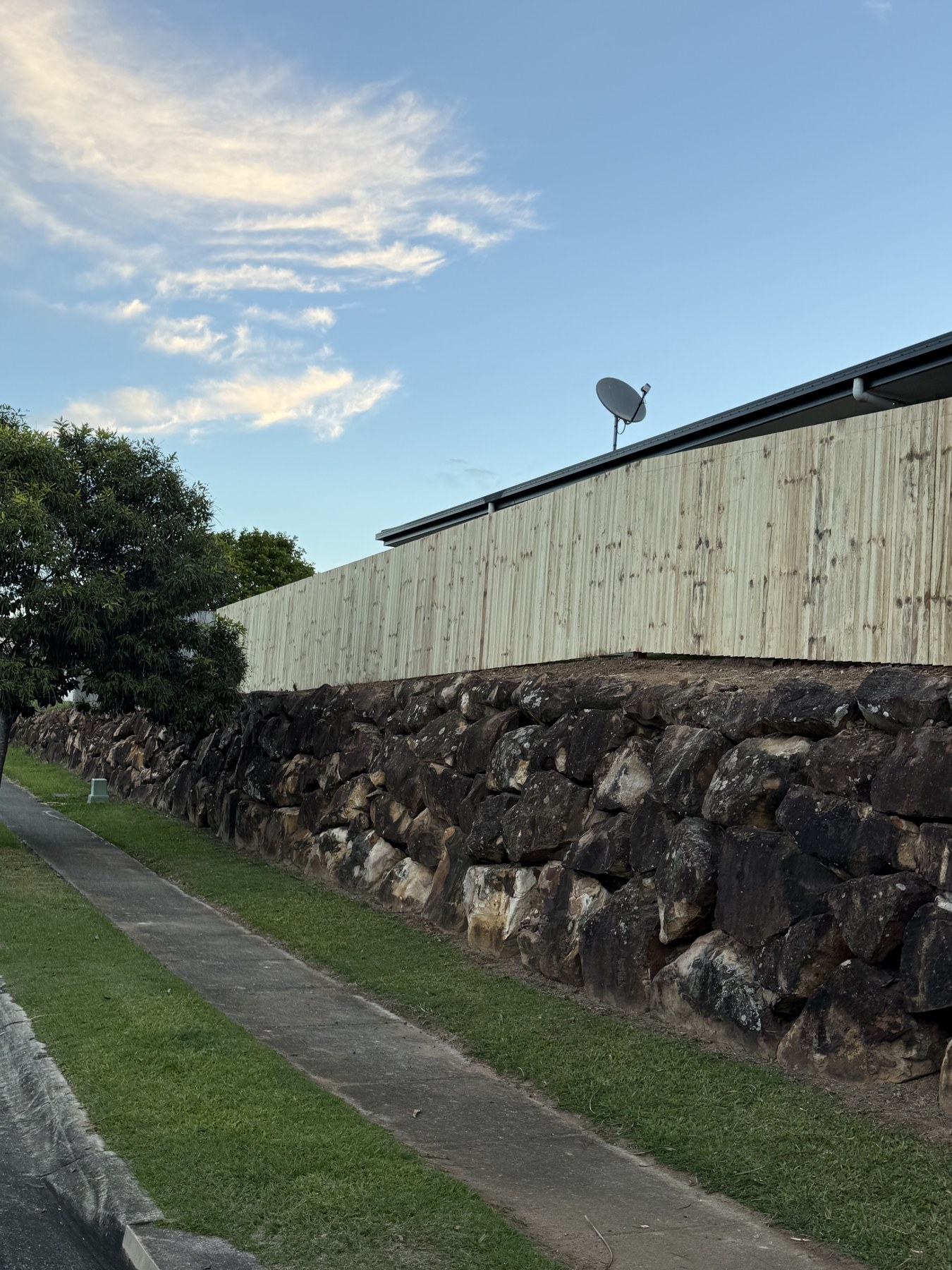 Timber boundary fence above a stone retaining wall