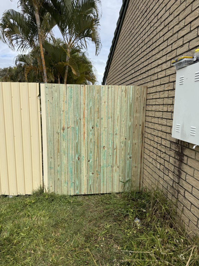 Timber side gate fitted between a brick wall and metal fence