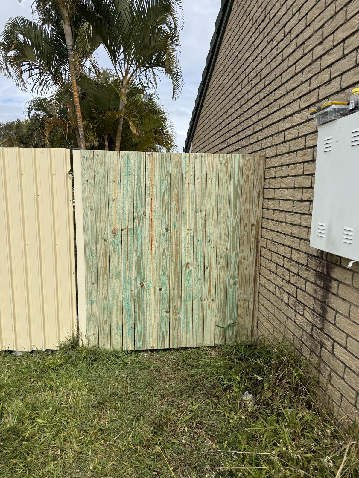 Timber side gate fitted between a brick wall and metal fence